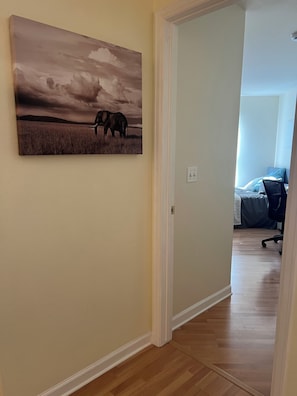 Un couloir orné d’un tableau représentant un éléphant, avec un lit visible au fond.
