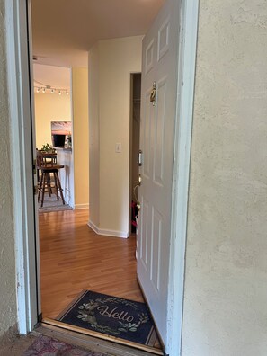 A hallway with a wooden floor leading to a dining area with a table and chairs. - Beautiful 2-bedroom condo in Boulder with fitness room, club house, pool, and AC (Boulder)
