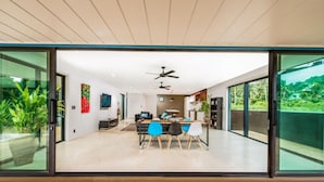 Interior moderno com área de refeições, cozinha e portas de vidro deslizantes que dão para uma varanda.