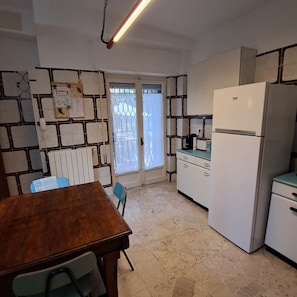 A compact kitchen with a refrigerator, a table, chairs, and a window. - Chalet di Târa: 1970s-era villa with a private pool, within walking distance of the beach, and pet-friendly (Anzio)