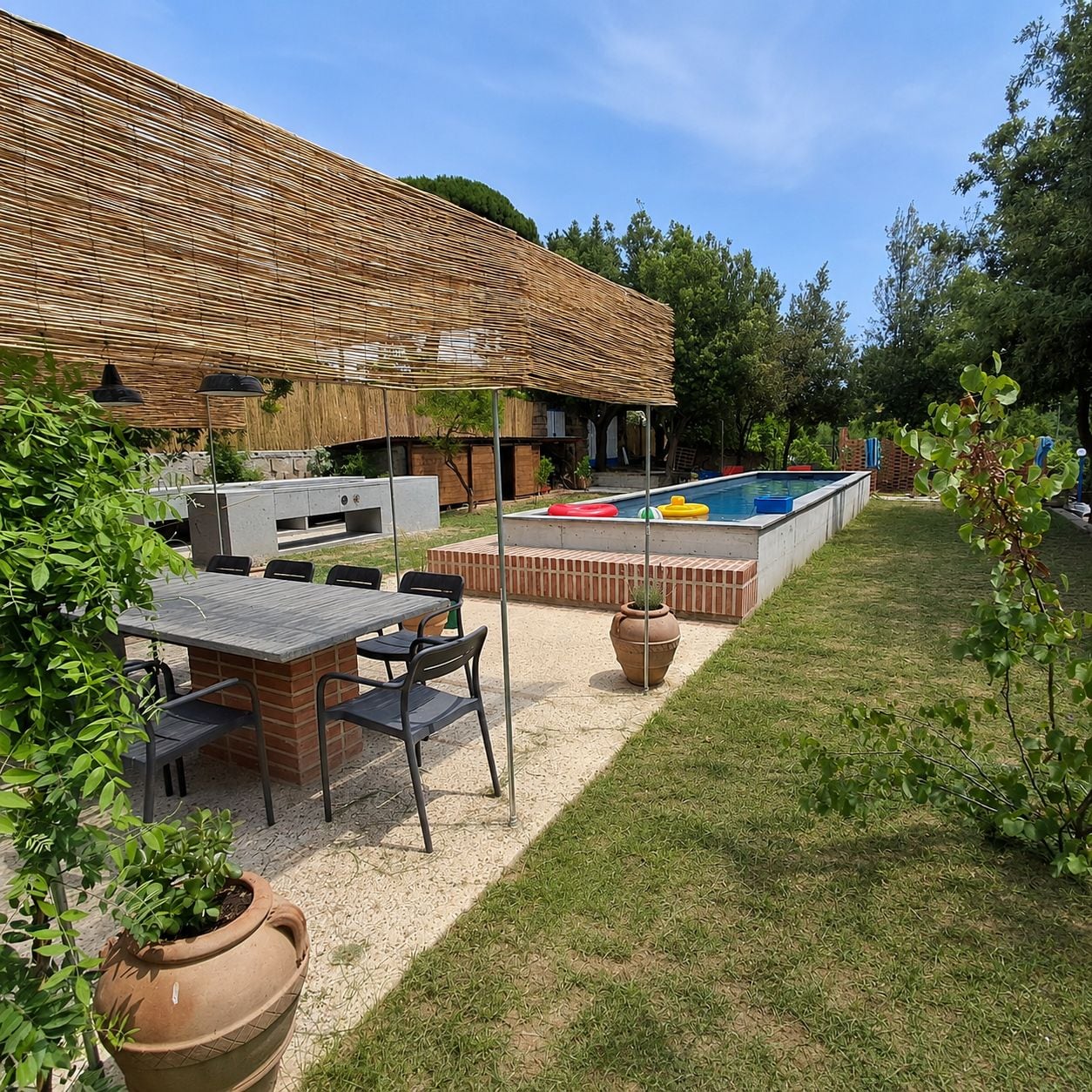 A backyard with a barbecue area, a pool, and a patio with seating.