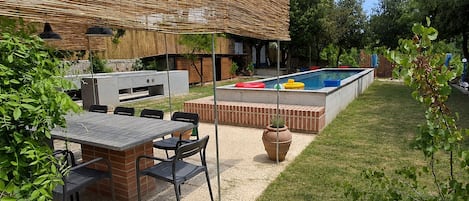 A backyard with a barbecue area, a pool, and a patio with seating.