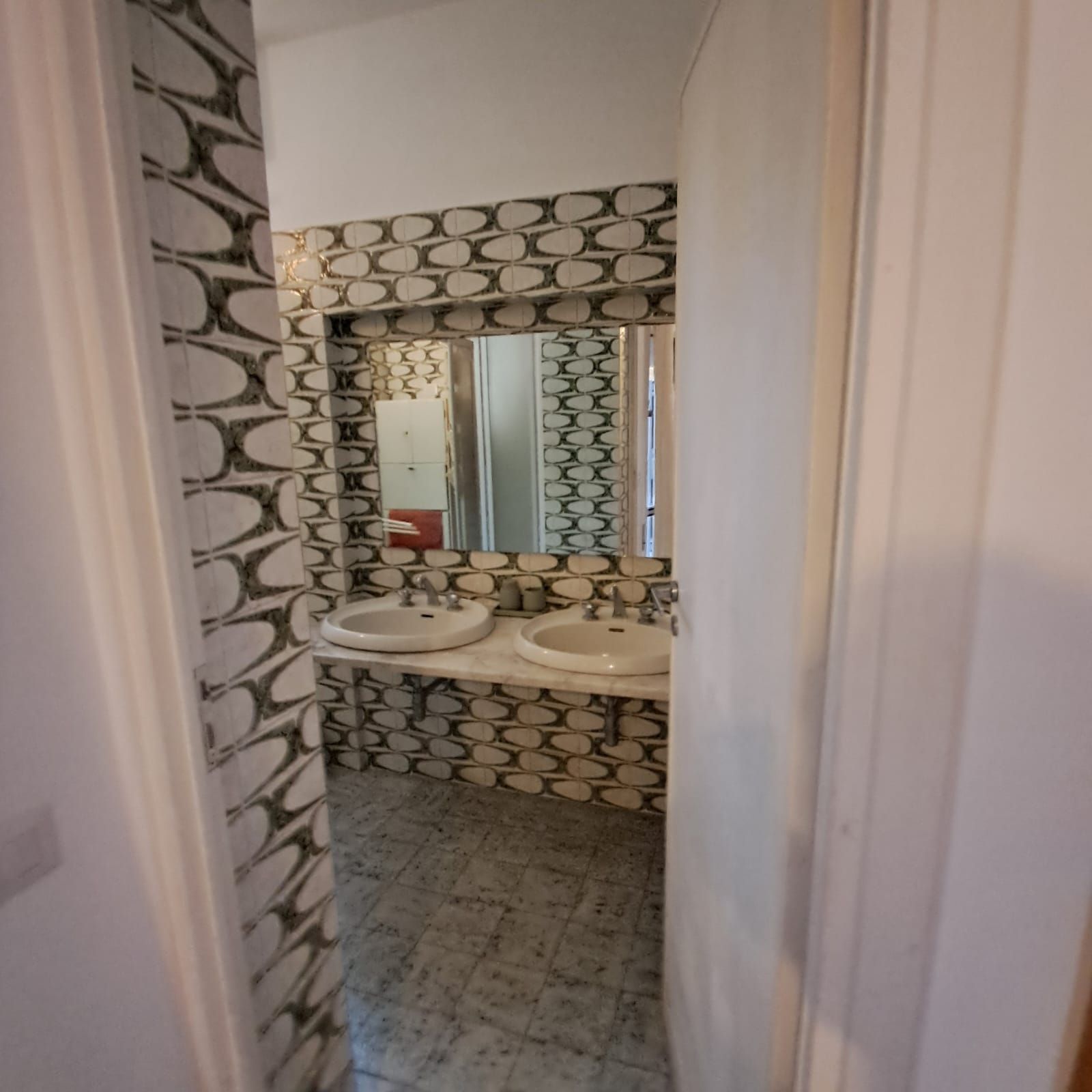 A bathroom with two sinks, a mirror, and a patterned wall.