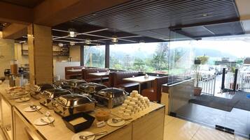 A buffet area with various food stations, seating arrangements, and a view of the outdoors.