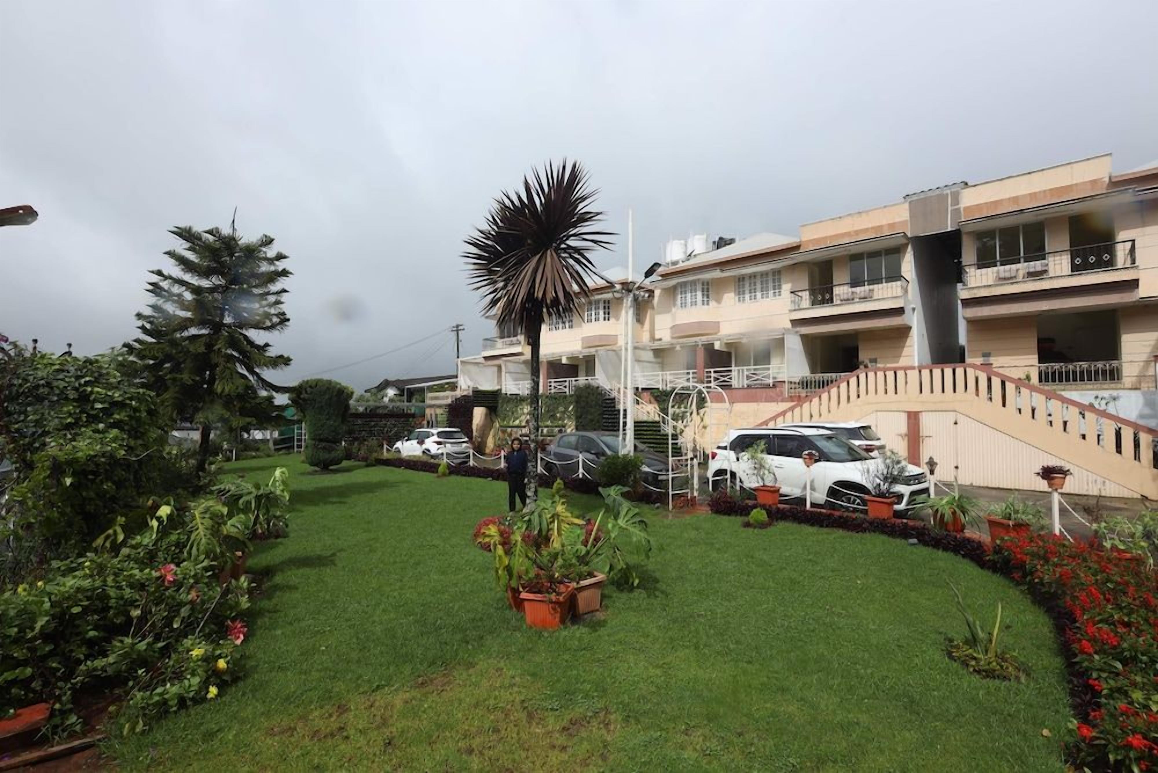 A residential building with a well-maintained lawn, potted plants, and a staircase leading to the upper floors.