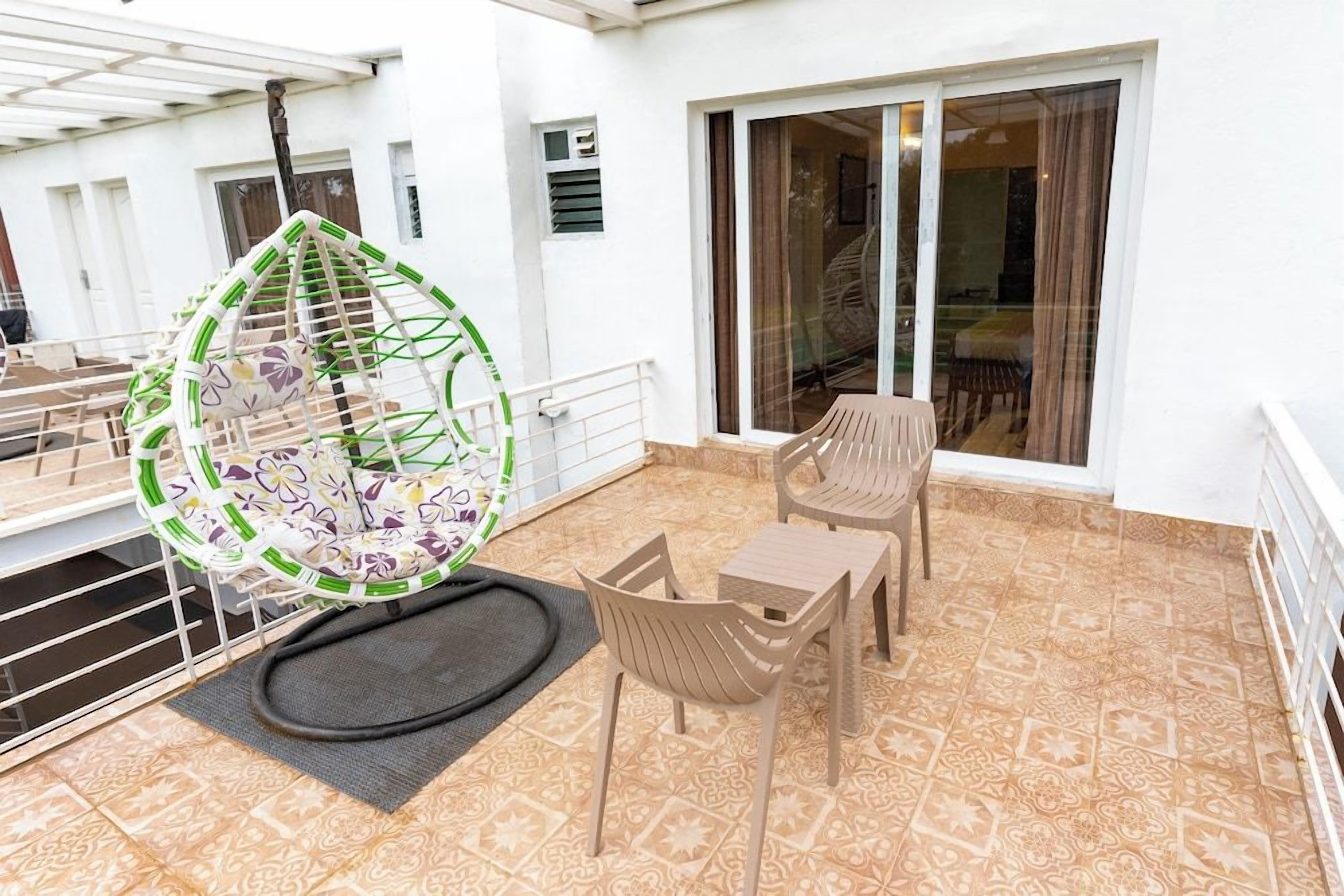 A balcony with a hanging chair, two tables, and chairs.