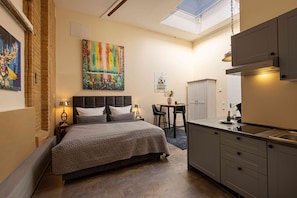 A compact bedroom with a bed, bedside tables, a desk, and a chair.