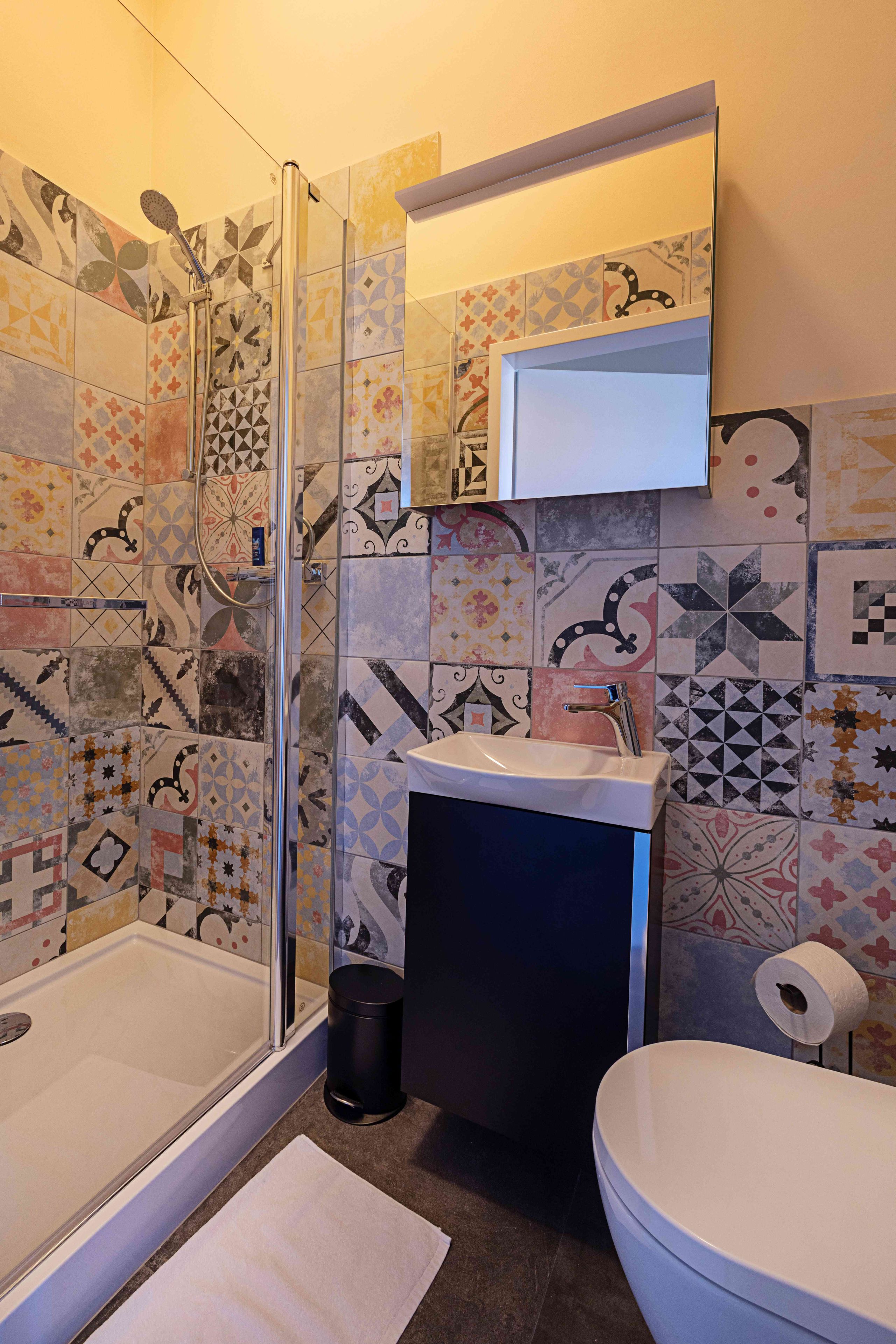 Ein Badezimmer mit Dusche, Waschbecken, Toilette und einem Spiegel über dem Waschbecken.