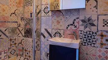 Ein Badezimmer mit Dusche, Waschbecken, Toilette und einem Spiegel über dem Waschbecken.