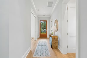 A hallway with a wooden door, a white wall, and a patterned rug. - Beach Escape, close to beach, new custom home (Isle Of Palms)