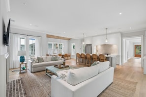 A spacious living area with a sofa, a dining table, and a kitchen area with bar stools. - Beach Escape, close to beach, new custom home (Isle Of Palms)