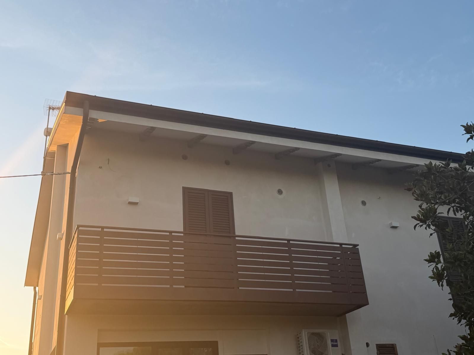 Un edificio moderno de dos pisos con techo plano y un balcón en el nivel superior.