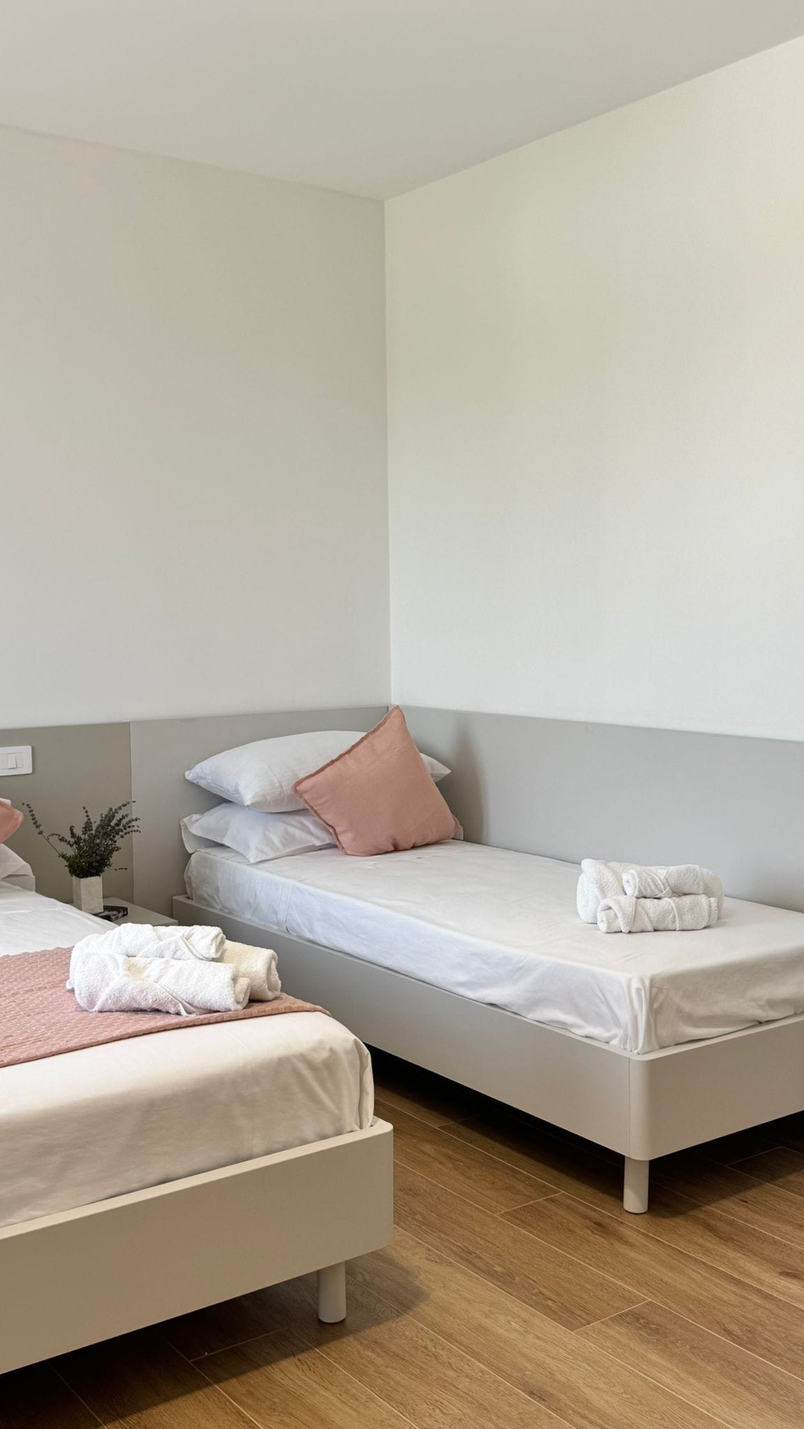 Ein Hotelzimmer mit zwei Einzelbetten, einem Nachttisch mit Lampe und einem kleinen Topfpflanzen.