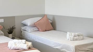 Ein Hotelzimmer mit zwei Einzelbetten, einem Nachttisch mit Lampe und einem kleinen Topfpflanzen.