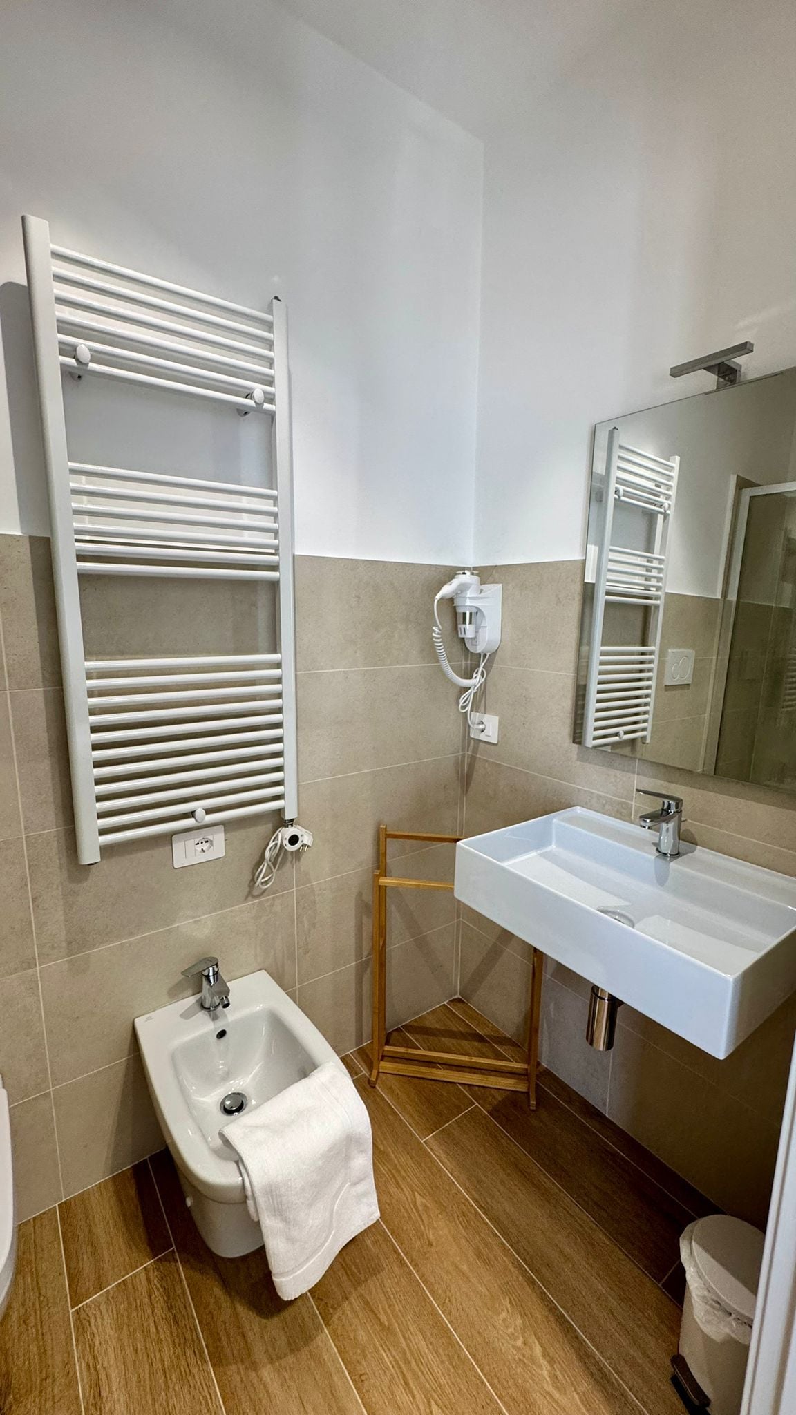 Ein modernes Badezimmer mit einer Bidet-Funktion, einem Waschbecken und einem Handtuchhalter.
