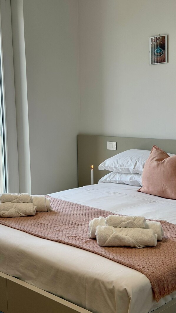 Una habitación de hotel con una cama, una mesita de noche con una vela y un cuadro colgado en la pared.