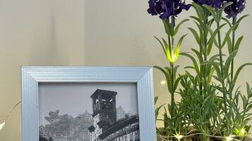 A framed black and white photograph of a historic building, a woven basket with purple flowers, and a string of lights on a table.