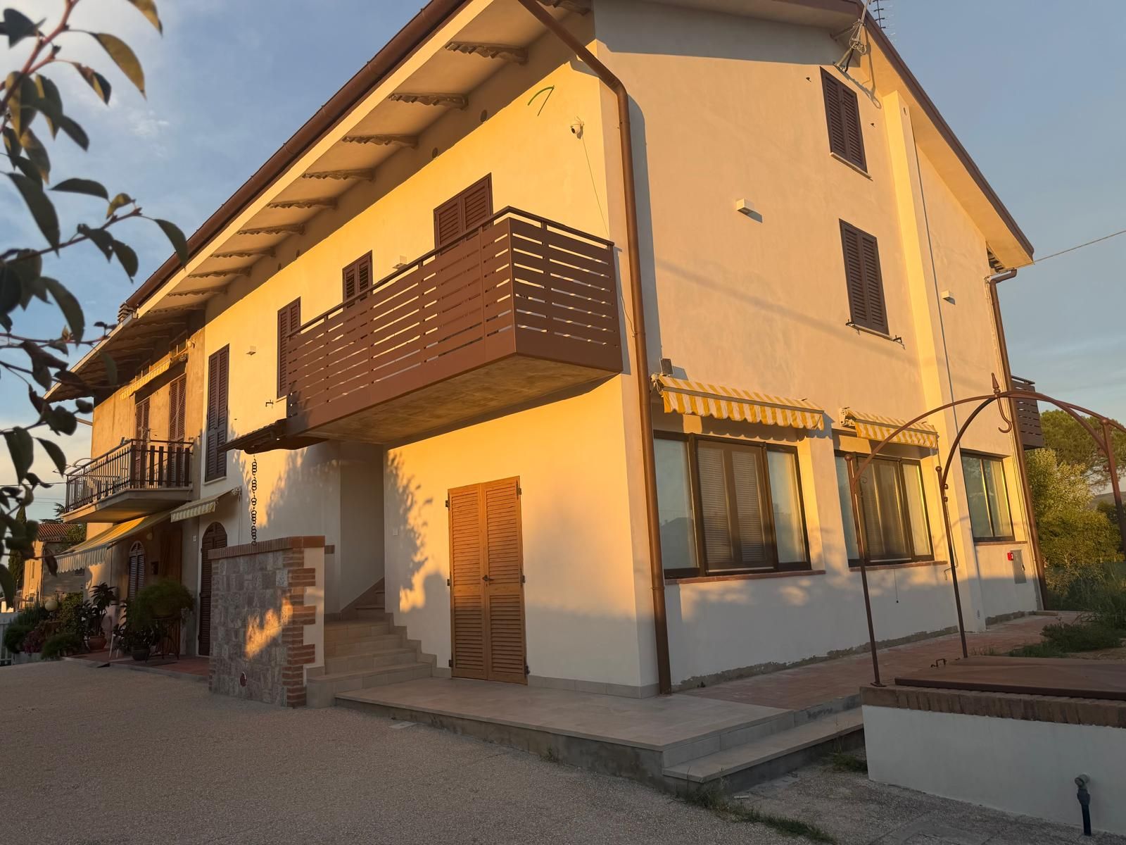 A two-story building with a balcony, a staircase, and a small outdoor area with plants.