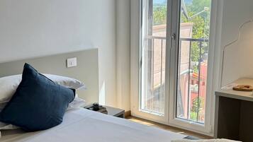 A hotel room with a bed, a window, and a view of the outdoors.