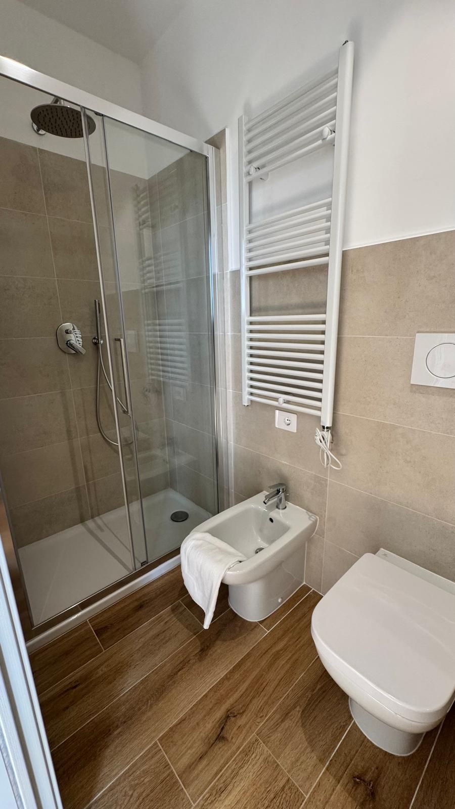 A bathroom with a glass-enclosed shower, a bidet, and a toilet.