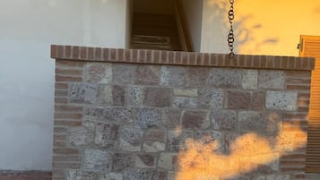 Um muro de pedra com um portão de metal, um hidrante vermelho e uma porta de madeira ao fundo.
