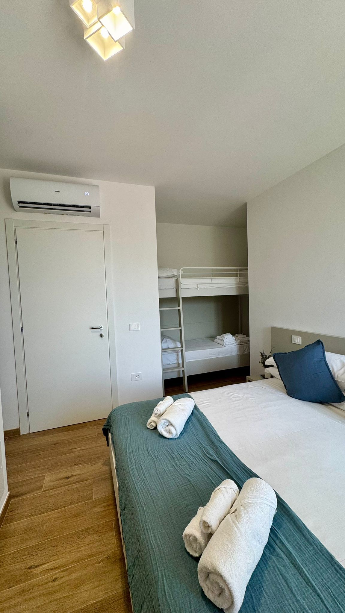 Une chambre d’hôtel équipée d’un lit superposé, d’un lit simple, d’une armoire et d’un appareil de climatisation.