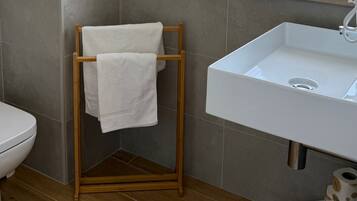 Un baño con inodoro, lavamanos, toallero y ventana con vistas a la vegetación.