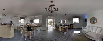 Un amplio espacio de sala con una mesa de comedor, sillas, un sofá y una araña.