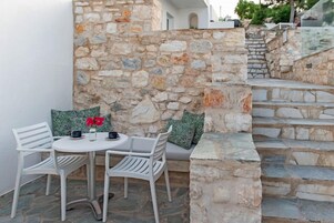 Un muro de piedra con un banco integrado y una mesa con sillas.