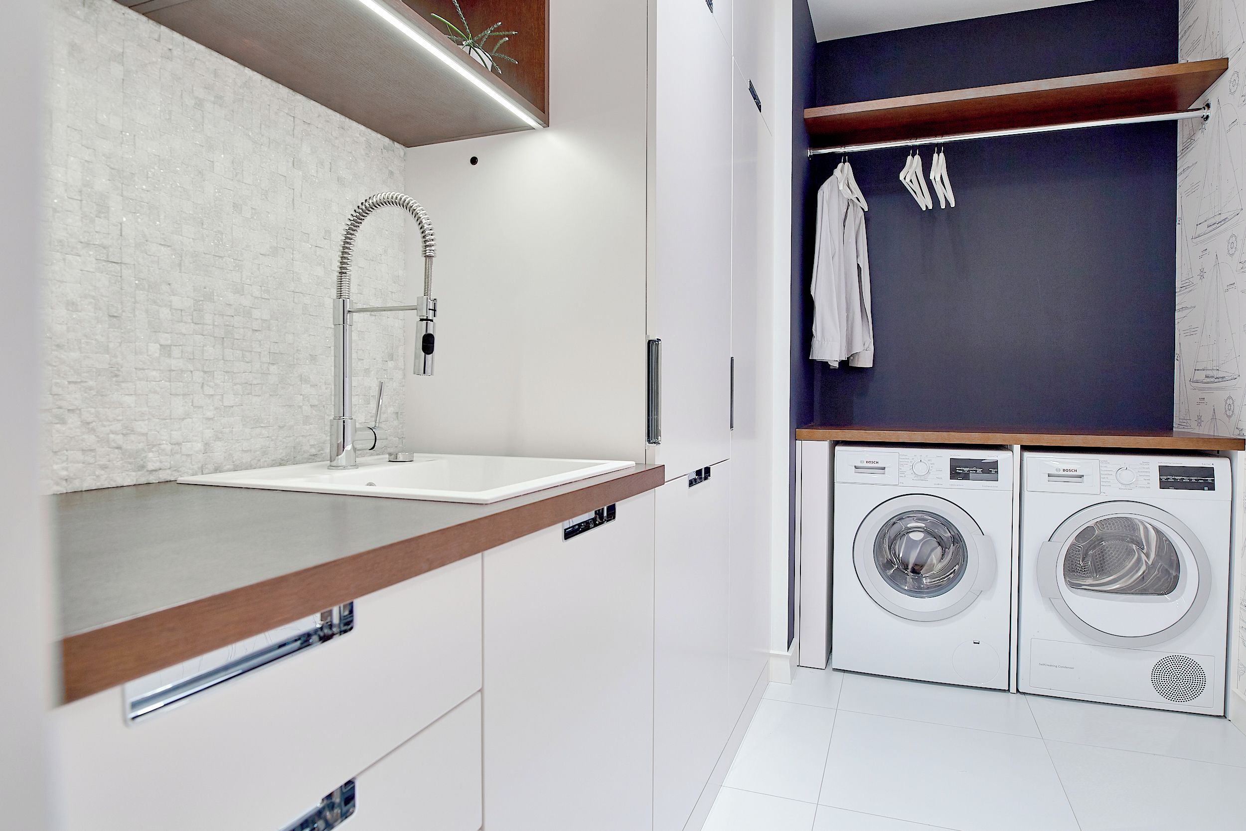 A modern bathroom with a sink, faucet, and a built-in washing machine.