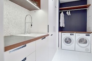 A modern bathroom with a sink, faucet, and a built-in washing machine.