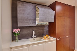 A kitchen with a built-in sink, a wooden cabinet, and a countertop with a vase of flowers.