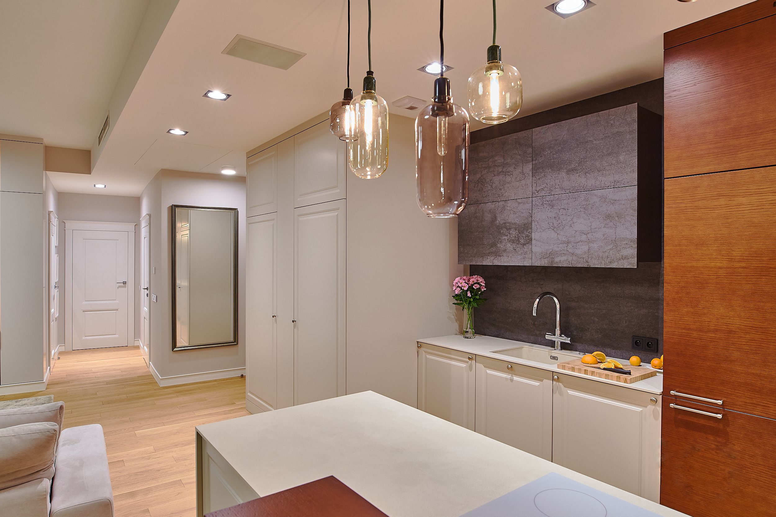 A modern kitchen with pendant lighting, a large mirror, and a built-in oven.