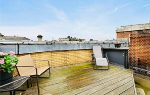 A rooftop terrace with a brick wall, a metal railing, and a pair of chairs. - Beautiful 3-Bedroom Home with 2 Bathrooms in London (London)
