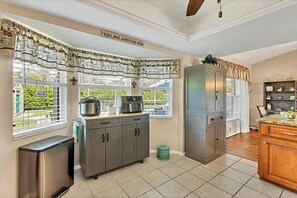 Eine Küche mit Kühlschrank, Herd und Schränken, ein Fenster mit Vorhängen und ein Schild über dem Fenster.