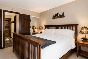 Ein Schlafzimmer mit einem hölzernen Bett, zwei Nachttischlampen, einem Nachttisch, einem Spiegel und einer Wandskulptur eines Bären.
