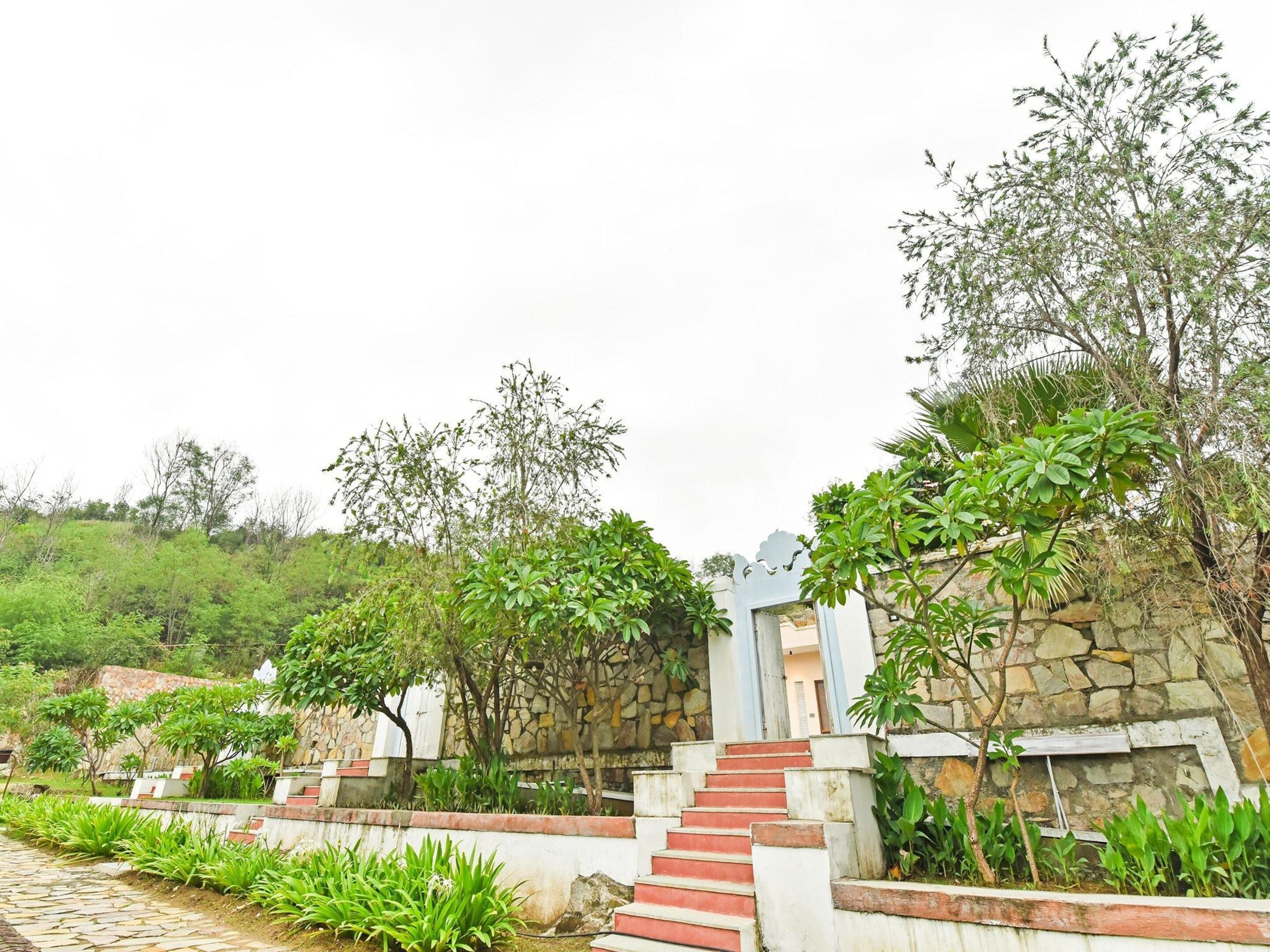 A staircase leading up to a stone wall with a gate, surrounded by lush greenery and plants.