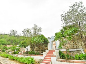 A staircase leading up to a stone wall with a gate, surrounded by lush greenery and plants.