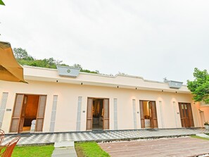 Un hotel con techo plano, varias puertas y un sendero a cuadros que lleva a la entrada.