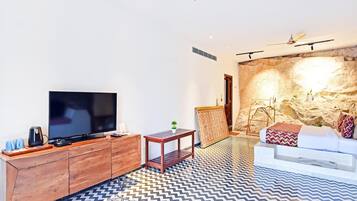 Ein modernes Wohnzimmer mit einem Flachbildfernseher, Holzmöbeln, einem gemusterten Boden und einer Steinwand.