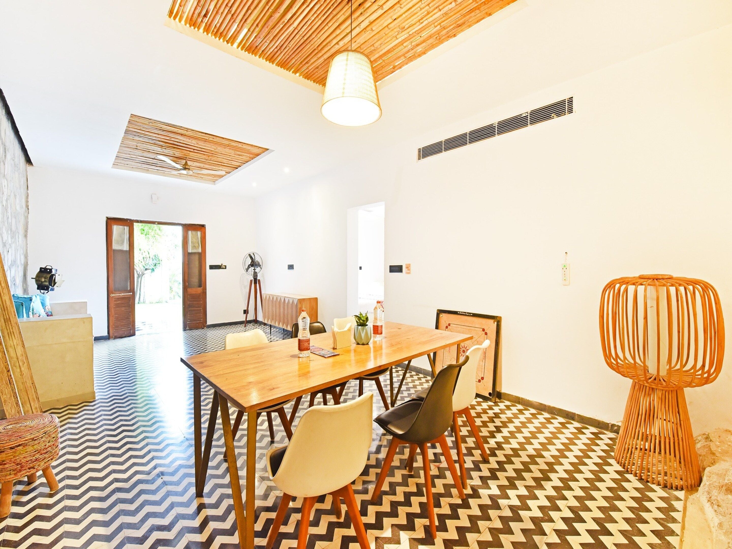 A modern interior with a wooden dining table, chairs, a patterned floor, and a ceiling fan.
