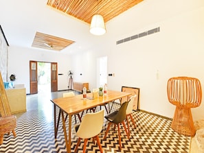 Un interior moderno con una mesa de comedor de madera, sillas, un suelo estampado y un ventilador de techo.