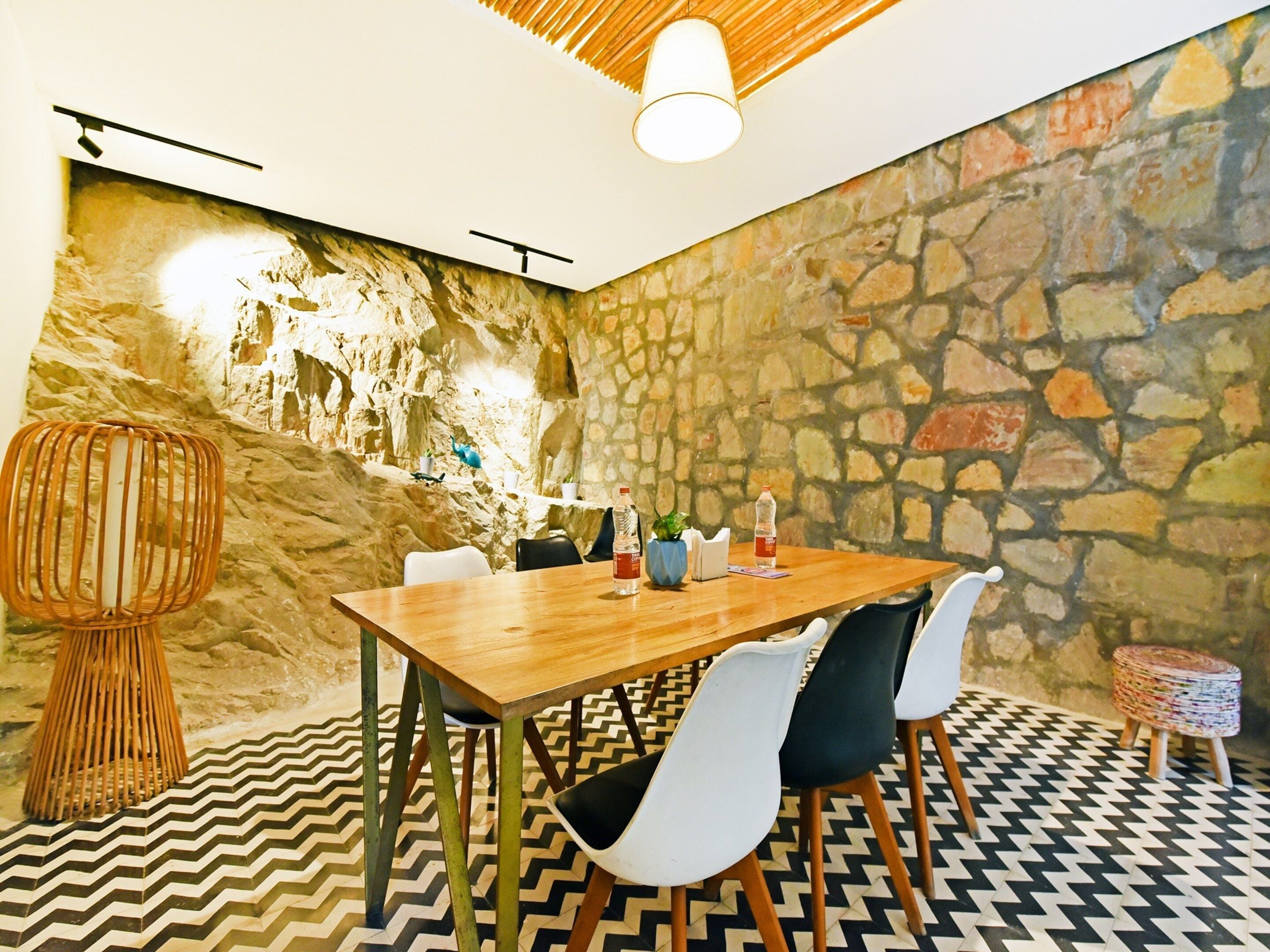 A dining area with a stone wall, a wooden table, and chairs.