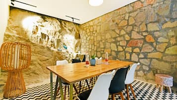 A dining area with a stone wall, a wooden table, and chairs.
