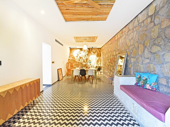 Un interior moderno con comedor, pared de piedra y suelo estampado.