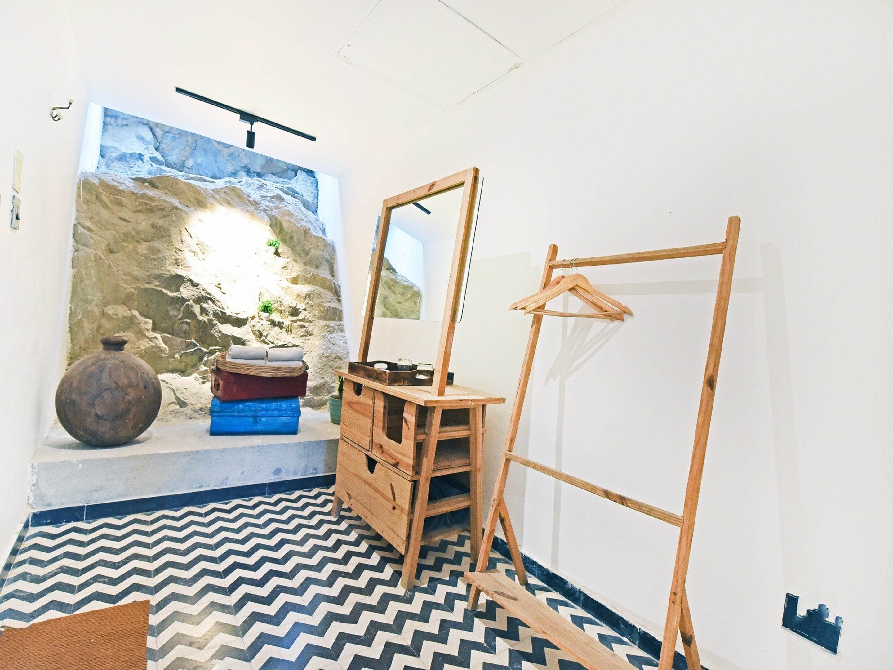 Ein Zimmer mit einem großen Spiegel, Holzmöbeln, einem gemusterten Boden und einer Wand mit strukturierter Gestaltung.