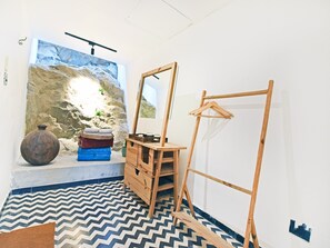 Una habitación con un espejo grande, muebles de madera, un suelo estampado y una pared con diseño texturizado.