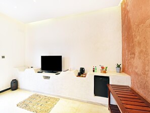 Una sala moderna con televisor de pantalla plana, cafetera, aperitivos y una pequeña planta en maceta.