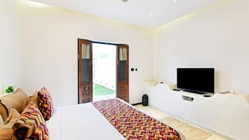 A hotel room with a bed, a television, and a door leading to an outdoor area.