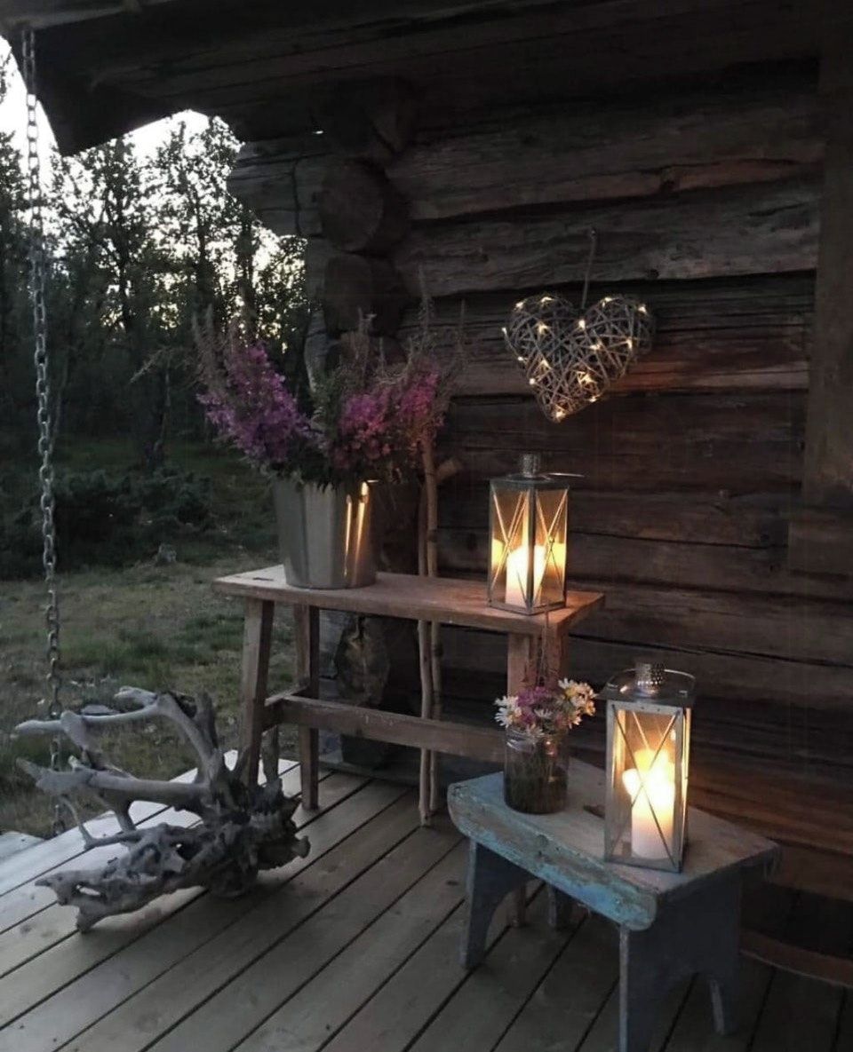 A rustic wooden cabin with a bench and lanterns.